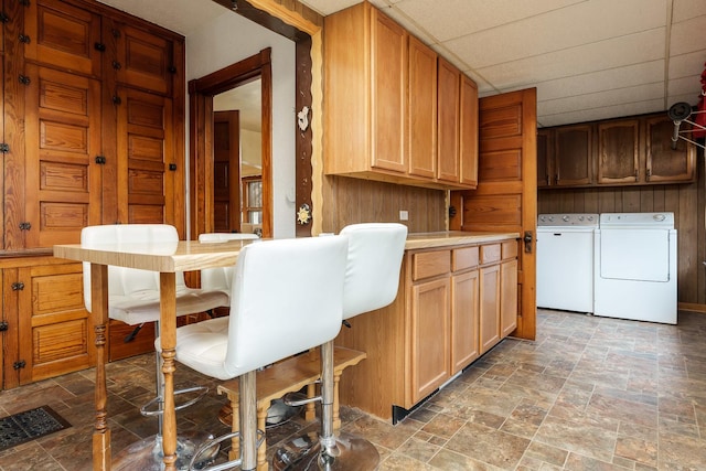 kitchen with a paneled ceiling, stone finish floor, light countertops, and washing machine and clothes dryer