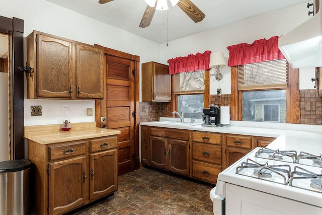 kitchen featuring light countertops, a sink, gas range gas stove, and exhaust hood