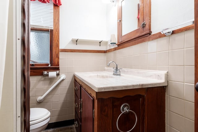 half bath with wainscoting, tile walls, toilet, and vanity