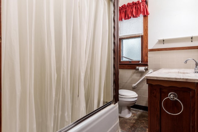 bathroom with shower / tub combo, wainscoting, toilet, vanity, and tile walls