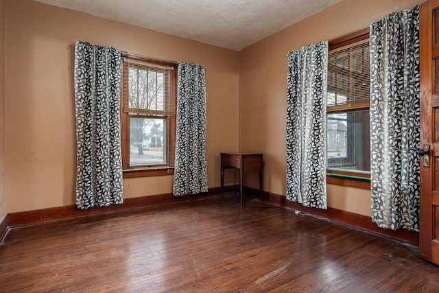 spare room featuring a textured ceiling, baseboards, and wood finished floors