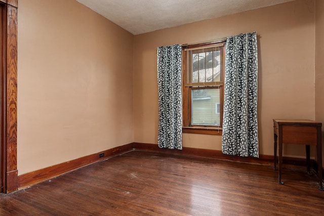 empty room featuring baseboards, dark wood finished floors, and a textured ceiling