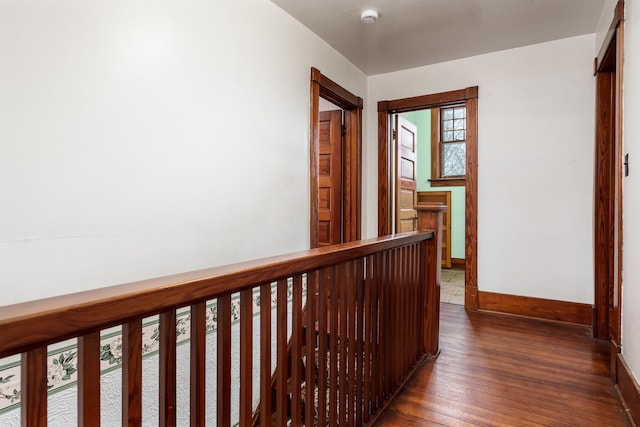 corridor featuring baseboards and hardwood / wood-style flooring