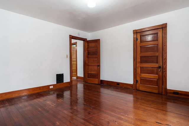 unfurnished room with wood-type flooring, visible vents, and baseboards