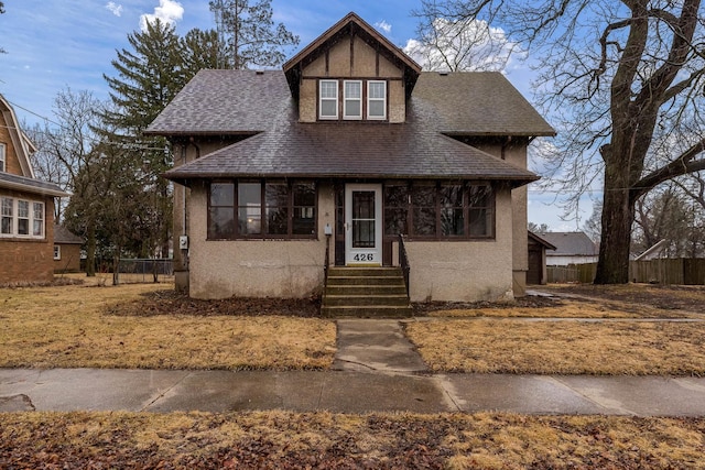 view of front of home with roof with shingles, fence, and stucco siding