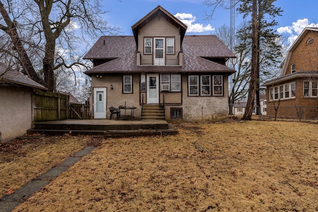 rear view of house with a shingled roof, fence, a balcony, and stucco siding