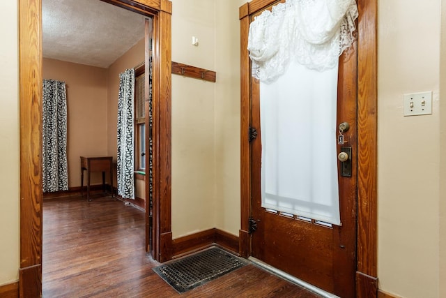 interior space with a textured ceiling, wood finished floors, visible vents, and baseboards