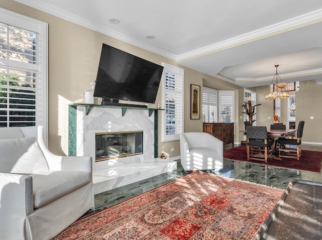 living area with crown molding, a fireplace, baseboards, and an inviting chandelier