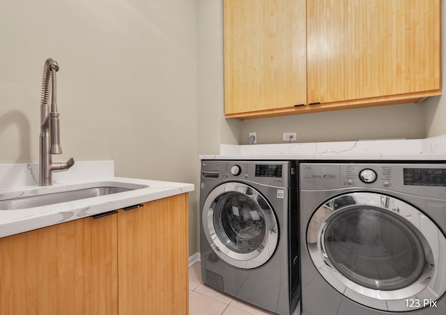 laundry area featuring cabinet space, a sink, washing machine and clothes dryer, and light tile patterned floors