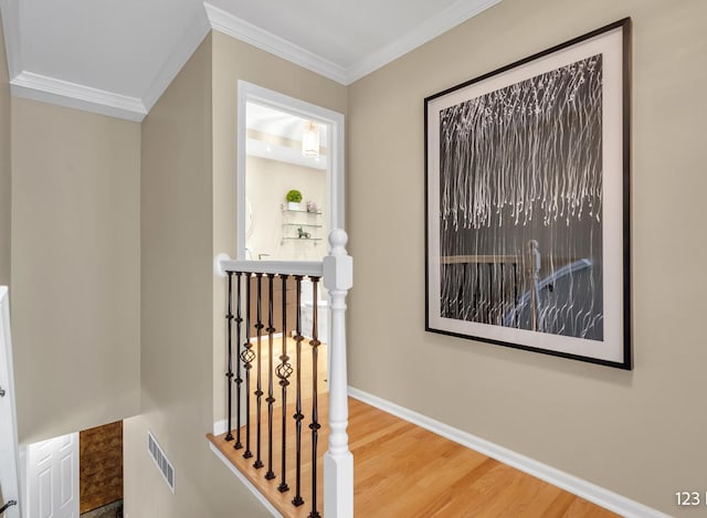 hallway with wood finished floors, an upstairs landing, visible vents, and crown molding