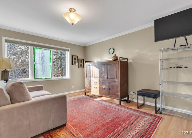 sitting room with light wood-style floors, crown molding, and baseboards