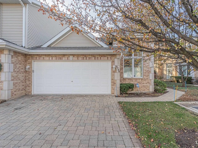 view of front of property with an attached garage, a shingled roof, decorative driveway, and brick siding