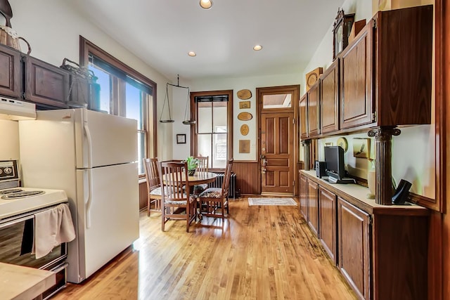 kitchen featuring white appliances, wainscoting, light wood-style flooring, under cabinet range hood, and recessed lighting