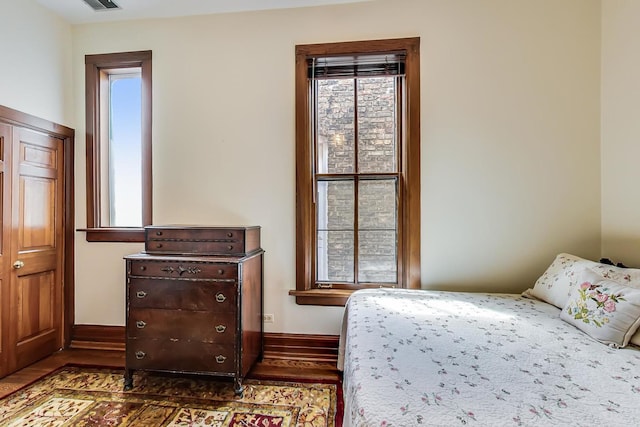 bedroom with visible vents, baseboards, and wood finished floors