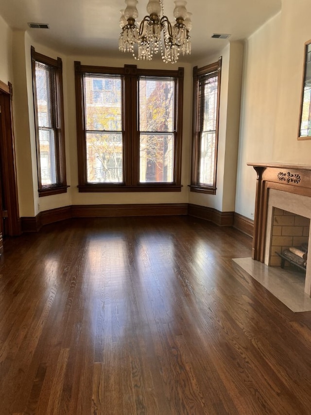 unfurnished living room with a high end fireplace, a wealth of natural light, visible vents, and an inviting chandelier