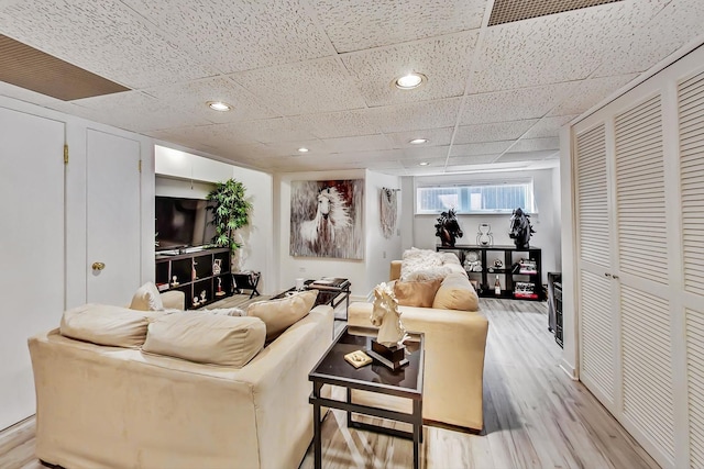 living room with recessed lighting, a paneled ceiling, and light wood-style floors