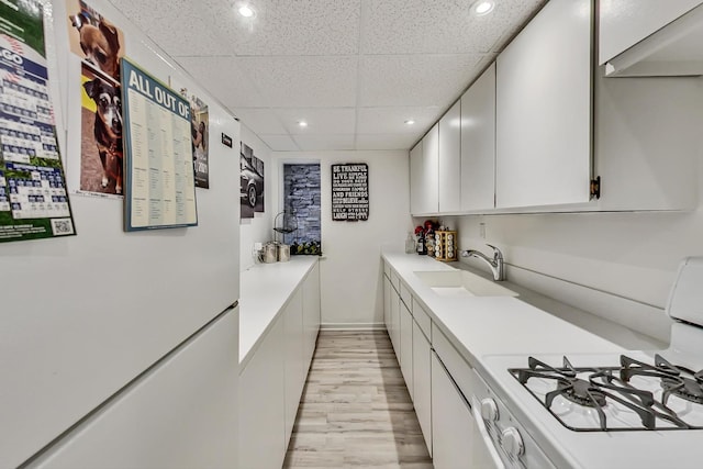 bar featuring light wood finished floors, recessed lighting, a sink, white appliances, and a drop ceiling