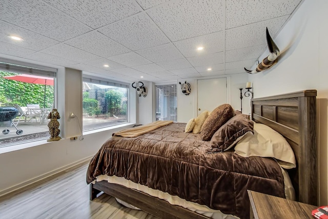 bedroom featuring a paneled ceiling, baseboards, wood finished floors, and recessed lighting