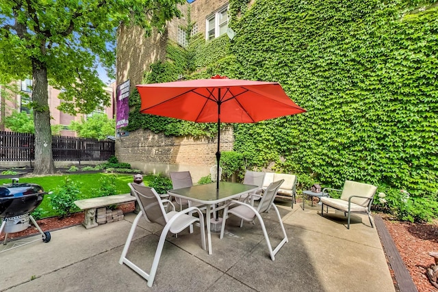 view of patio featuring a grill, fence, and outdoor dining area