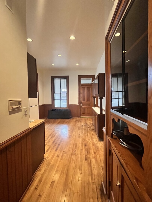 interior space featuring light wood-style flooring, recessed lighting, visible vents, wainscoting, and radiator