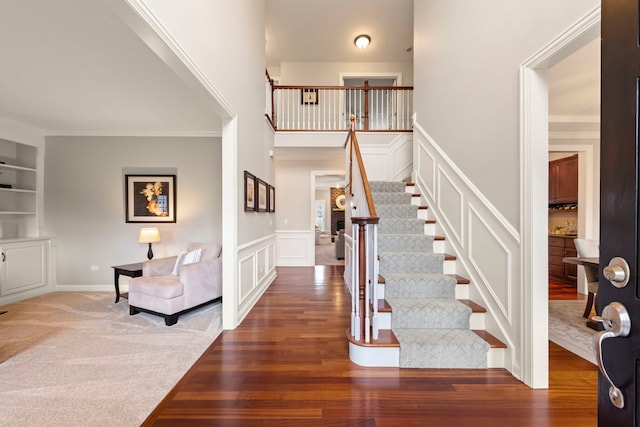 foyer entrance featuring stairs, carpet floors, wood finished floors, and a decorative wall