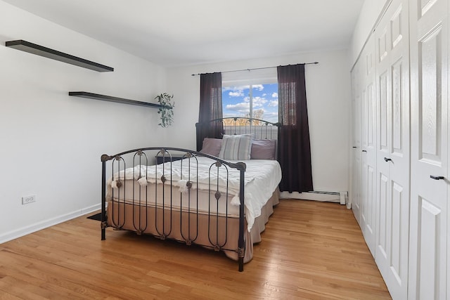 bedroom with light wood-style flooring, baseboards, a closet, and baseboard heating