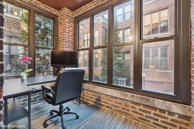 home office with carpet floors and brick wall