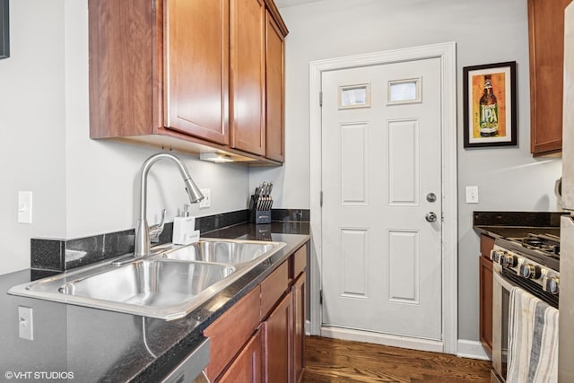 kitchen with dark wood-type flooring, gas stove, brown cabinets, and a sink