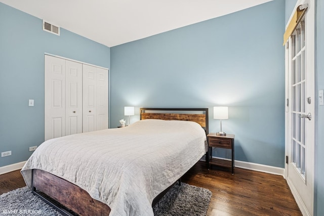 bedroom with a closet, wood finished floors, visible vents, and baseboards