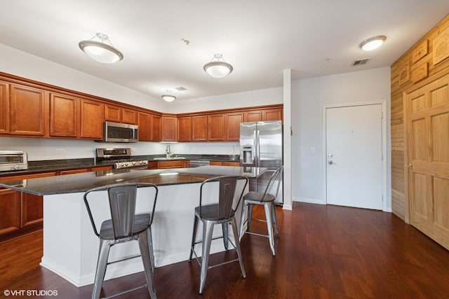 kitchen with a breakfast bar area, dark wood-style floors, visible vents, appliances with stainless steel finishes, and a center island