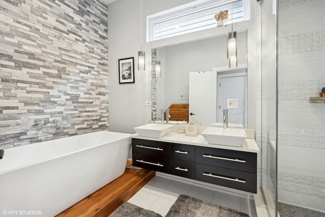 bathroom featuring double vanity, a freestanding bath, a sink, and tile patterned floors