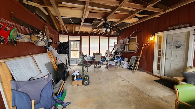 interior space featuring ceiling fan, wooden walls, and concrete flooring