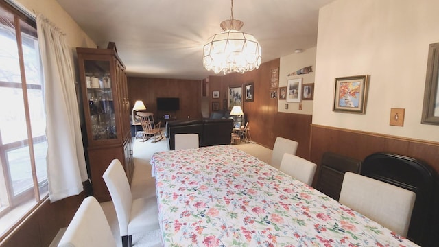 dining room featuring a chandelier, a wainscoted wall, and wooden walls