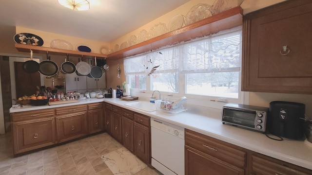 kitchen with a toaster, white dishwasher, light countertops, and a sink