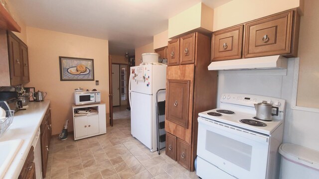 kitchen featuring brown cabinets, light countertops, a sink, white appliances, and under cabinet range hood