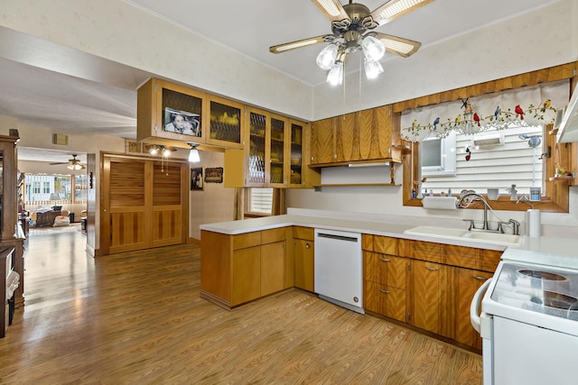 kitchen with light countertops, light wood-style flooring, a sink, white appliances, and a peninsula