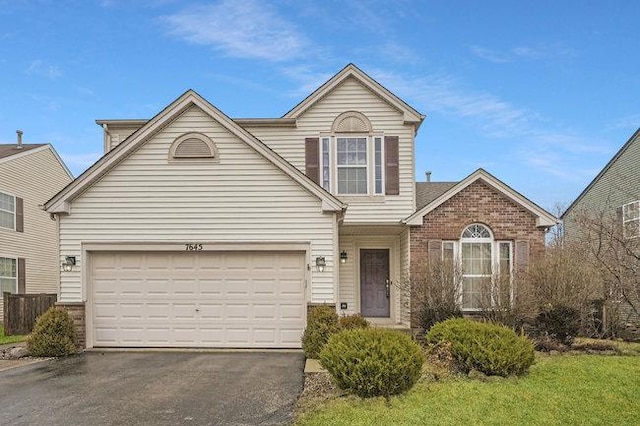 traditional-style house featuring driveway, brick siding, and an attached garage