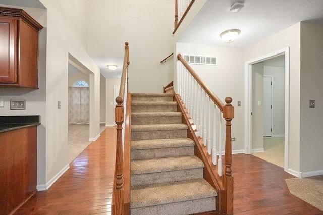 stairway featuring baseboards, visible vents, and hardwood / wood-style floors