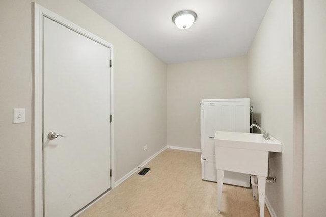 laundry area with laundry area, visible vents, baseboards, light wood-style floors, and a sink