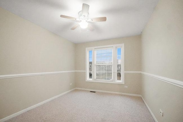 unfurnished room with carpet floors, visible vents, ceiling fan, and baseboards