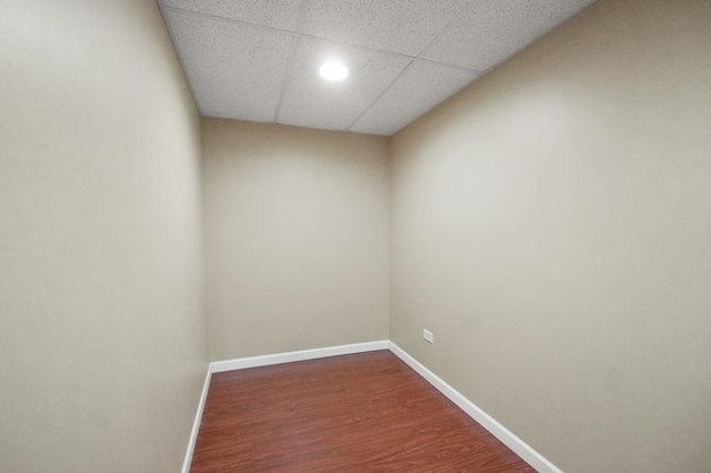 spare room with a drop ceiling, baseboards, and wood finished floors