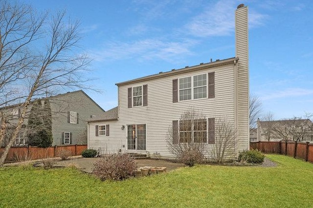 rear view of property with a patio, a yard, a chimney, and fence