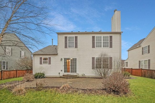 rear view of property featuring a yard, a chimney, a patio area, and fence