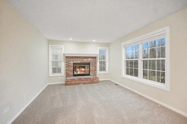 unfurnished living room with carpet floors, a brick fireplace, baseboards, and recessed lighting