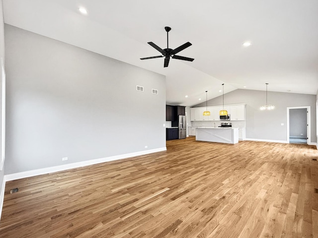 unfurnished living room featuring ceiling fan with notable chandelier, vaulted ceiling, light wood-style flooring, and baseboards