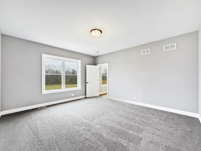 carpeted spare room with visible vents and baseboards