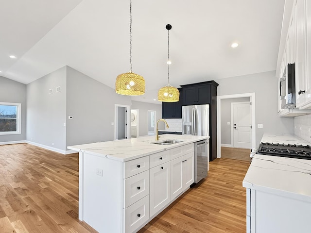 kitchen featuring appliances with stainless steel finishes, a sink, backsplash, and an island with sink