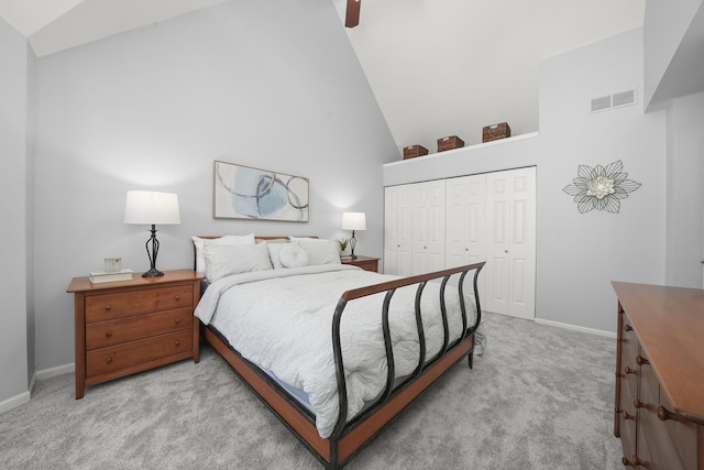 bedroom with a ceiling fan, baseboards, high vaulted ceiling, a closet, and light colored carpet