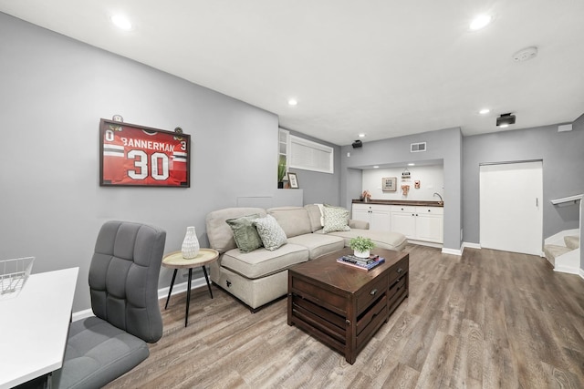 living area featuring light wood finished floors, visible vents, baseboards, stairs, and recessed lighting