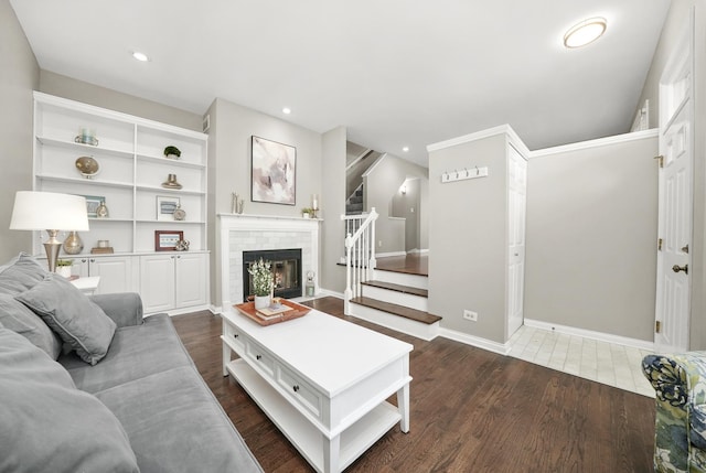 living area with recessed lighting, a brick fireplace, dark wood-style flooring, and stairs